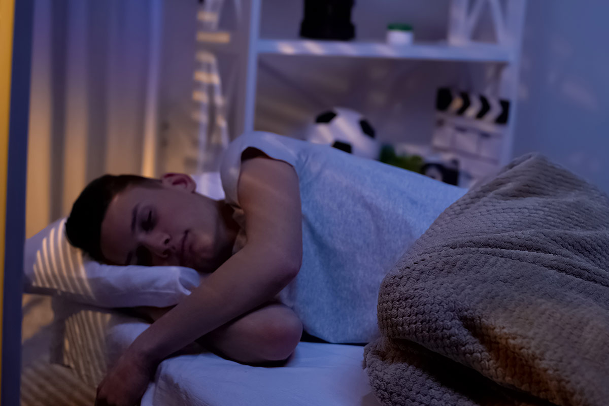 photo of teenage boy sleeping in darkened room